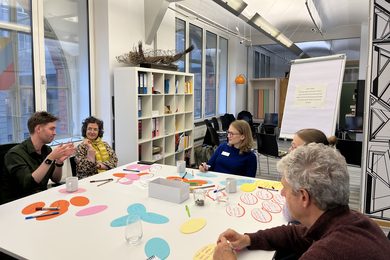 Eine Gruppe von Workshop-Teilnehmenden diskutieren an einem Tisch